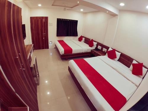a bedroom with two beds with red and white sheets at Hotel Nawanagar Residency in Jamnagar