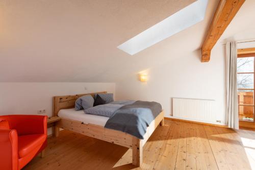 a bedroom with a bed and a orange chair at Gugg Hof - Familie Hölzl in Hopfgarten im Brixental