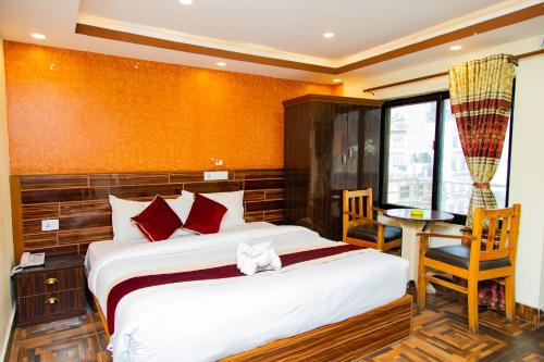 a bedroom with a bed and a table and a chair at Hotel Everest Regency in Kathmandu