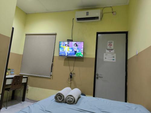 um quarto de hospital com uma cama e uma televisão na parede em PROMOSIA GUEST HOUSE em Surabaya