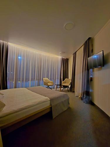 a bedroom with a bed and two chairs in front of a window at Wellotel Chornomorsk in Chornomorsk