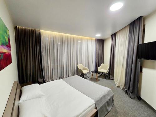 a hotel room with a bed and two chairs in it at Wellotel Chornomorsk in Chornomorsk