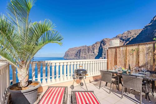 Un balcón con una mesa y una palmera en Los Gigantes Buenavista Ocean View Apartment, en Acantilado de los Gigantes