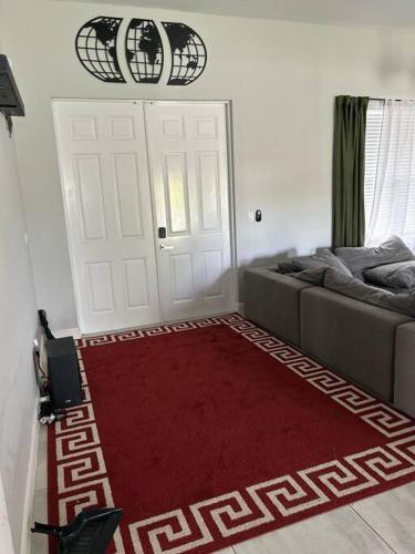 a living room with a red rug in front of a door at Canal Park Paradise in Port Saint Lucie