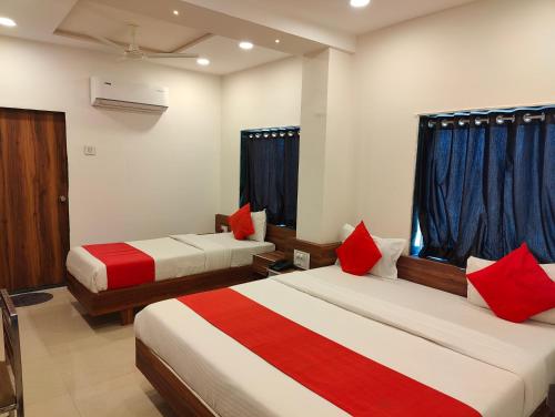 a hotel room with two beds with red pillows at Hotel Nawanagar Residency in Jamnagar