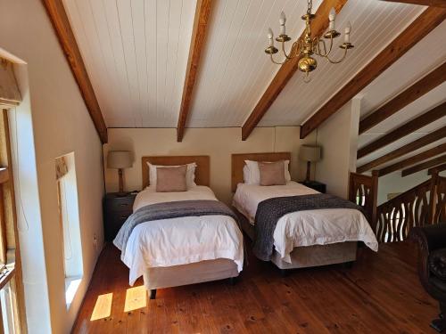 two beds in a room with wooden floors at Valley View Eco Country Estate - Paradise in the Winelands in Villiersdorp
