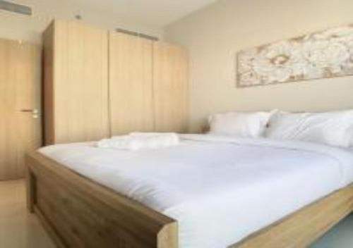 una camera da letto con un grande letto con lenzuola e cuscini bianchi di Key View - Navitas Tower A a ‘Ūd al Bayḑāʼ