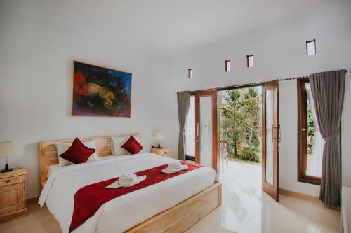 De Casa Ananda Nusa Penida في نوسا بينيدا: غرفة نوم بسرير كبير ومخدات حمراء