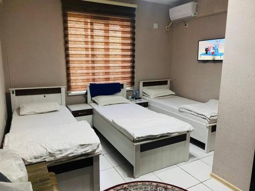 une chambre à l'hôpital avec trois lits et une télévision dans l'établissement ObodHotel, à Douchanbé