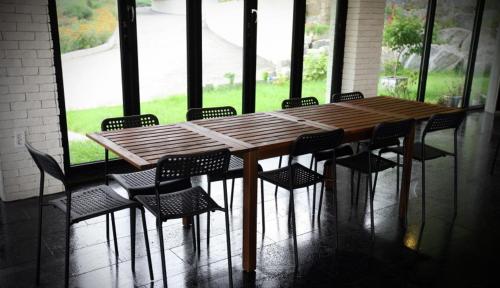 una mesa de madera y sillas en una habitación con ventanas en 91 Stay, en Chuncheon