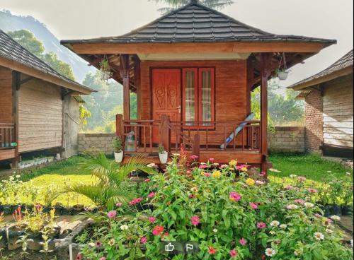 a small wooden house with a garden with flowers at Puncak Rinjani Lodge in Sembalun Lawang