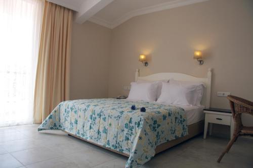 a bedroom with a bed and a chair and a window at Oludeniz Blue Lagoon Beach Hotel in Fethiye