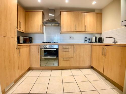 a kitchen with wooden cabinets and a stove top oven at Central Retford 2 bed quiet apartment with parking in Retford
