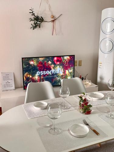 a dining room table with wine glasses and a television at Ulsan stay in Ulsan