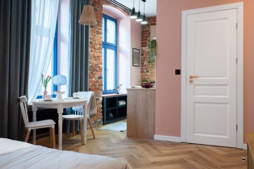 a bedroom with a bed and a table and a room with pink walls at 1555 Apartments V in Toruń