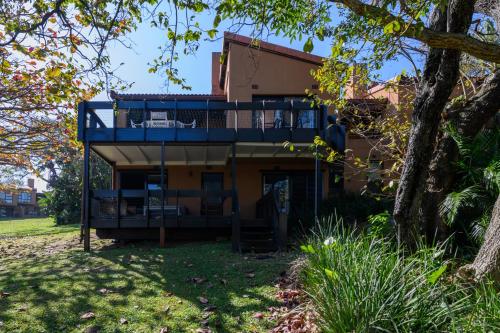 a house with a blue deck and a tree at San Lameer Villa 2845 - 3 Bedroom Classic - 6 pax - San Lameer Rental Agency in Southbroom