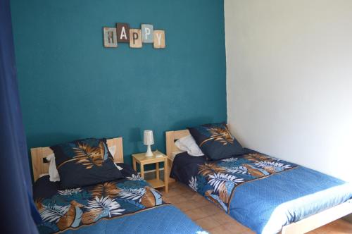 une chambre avec deux lits et un mur bleu dans l'établissement Gites du Château de Lestang, à Auzits