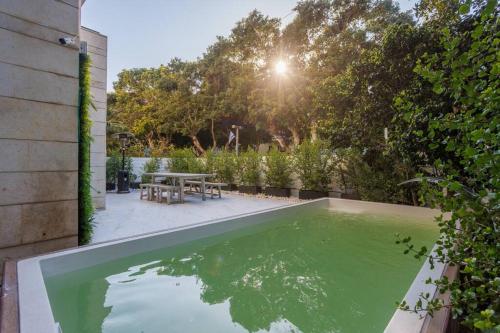 basen z zieloną wodą w ogródku ze stołem w obiekcie Rothschild Modern Apartment with a Pool w Tel Awiwie