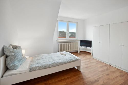 - une chambre blanche avec un lit et une télévision dans l'établissement Nice Apartment in Bremerhaven, à Bremerhaven