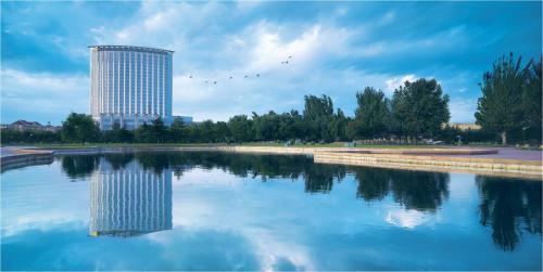 a building with a reflection in a body of water at Shangri-La Baotou in Baotou