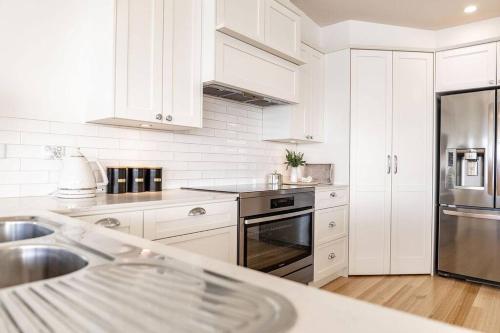 a kitchen with white cabinets and a stainless steel refrigerator at Nautilus ~ Bay of Fires in Binalong Bay