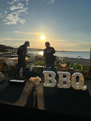 deux hommes debout devant une table avec un panneau bbb dans l'établissement Chill Chill House, à Shimen