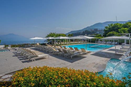 a pool with chairs and umbrellas next to the ocean at Hotel Le Axidie in Vico Equense
