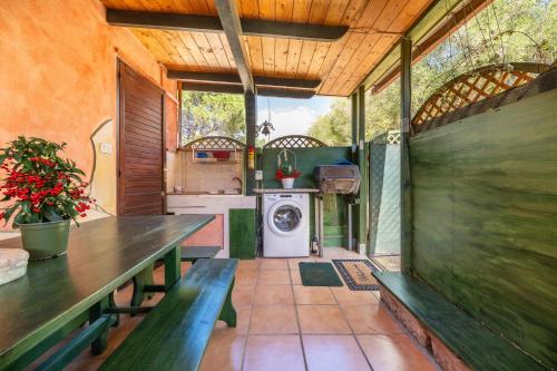 an outdoor kitchen with benches and a washer and dryer at Is Zuddas in Geremèas