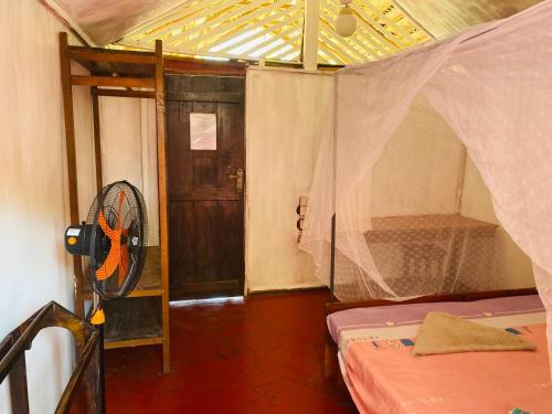 een kamer met een ventilator en een deur bij Rainbow Village Cabanas in Arugam Bay
