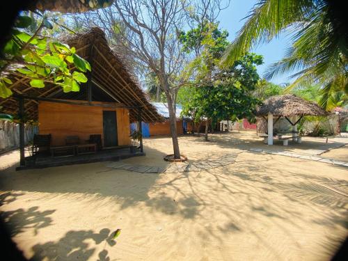 Rainbow Village Cabanas في آروغام باي: منزل صغير مع سقف من القش على الشاطئ