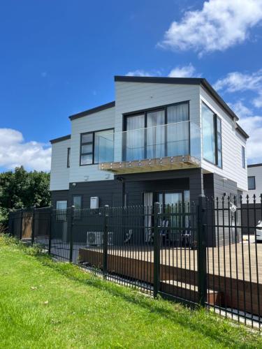 a house with a black fence in front of it at Relax by the Tamaki River in Auckland