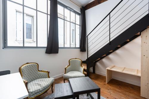 2 chaises et une table dans une chambre avec fenêtres dans l'établissement Le Victor Hugo - Centre-ville Bordelais, à Bordeaux