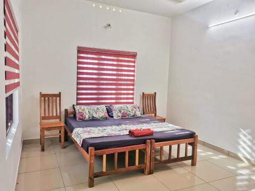 a bed sitting in a room with two chairs at TROPICAL STORIES in Varkala