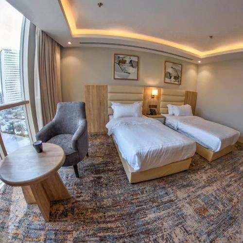 a hotel room with two beds and a chair at Samtinn Hotel King Fahad in Riyadh