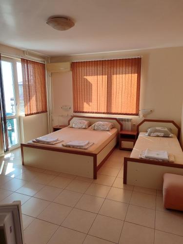 two beds in a room with windows at Milchevi Guesthouse in Sozopol