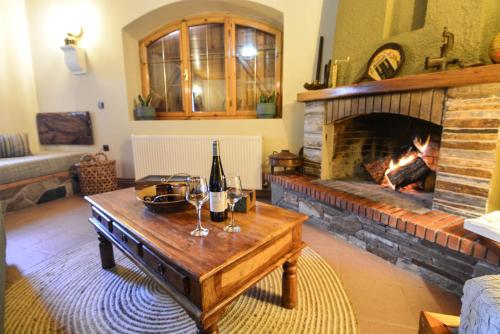a living room with a fireplace and a table with wine glasses at Capris Rustic Ηouse with Mountain View in Archaia Feneos