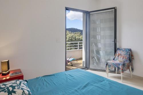 um quarto com uma cama, uma cadeira e uma janela em Casa Funtana em Biguglia