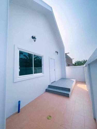 Habitación blanca con ventana y escalera en Minimalism Pool Villa, en Thap Sakae