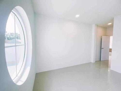 Habitación con una gran ventana circular en una pared blanca. en Minimalism Pool Villa, en Thap Sakae