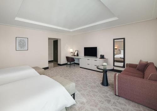 a bedroom with a bed and a couch and a tv at Address Jabal Omar Makkah in Makkah