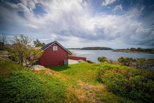 een rood huis op een heuvel naast een waterlichaam bij Kristiansand Feriesenter in Kristiansand