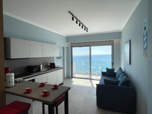sala de estar con sofá, mesa y cocina en Charaki Sea Breeze Modern Studio with Balcony, en Charaki