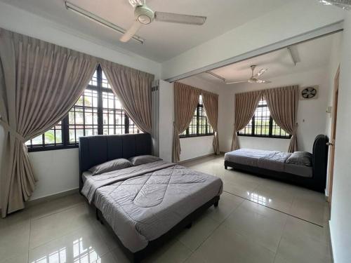 a bedroom with two beds and two windows at Pelangi Indah 8 Rooms Corner Pool Table in Ulu Tiram