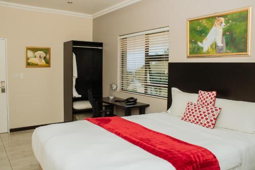 a bedroom with a bed with a red blanket on it at Heavenly Boutique Hotel in Johannesburg