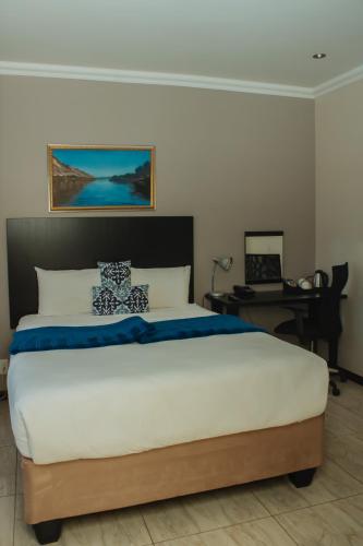 a bedroom with a large bed and a desk at Heavenly Boutique Hotel in Johannesburg