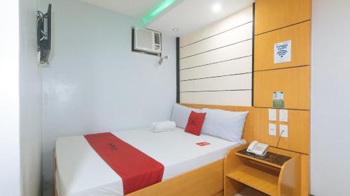 um pequeno quarto com uma cama e um telefone em RedDoorz at Ranchotel Alabang em Manila