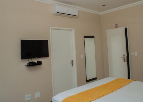 a bedroom with a bed and a tv on the wall at Heavenly Boutique Hotel in Johannesburg