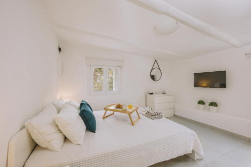 a white bedroom with a bed and a tv at ARGi House in Maroulás