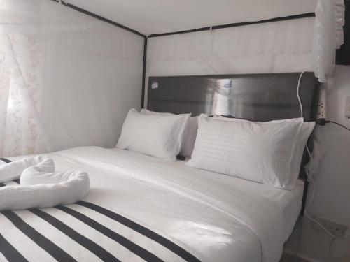 uma cama branca com almofadas pretas e brancas em Skybeach apartment em Kisumu