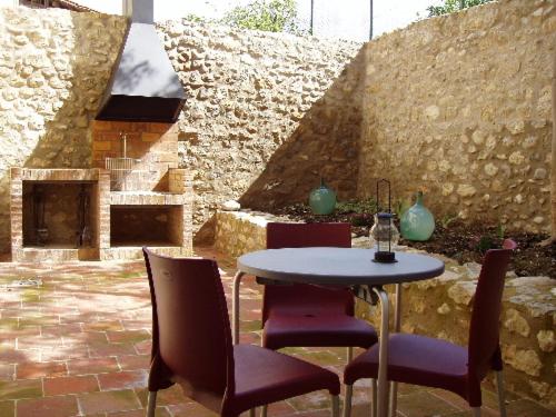 un patio con mesa, sillas y pared de piedra. en Apartamentos Bergantes, en Ortells